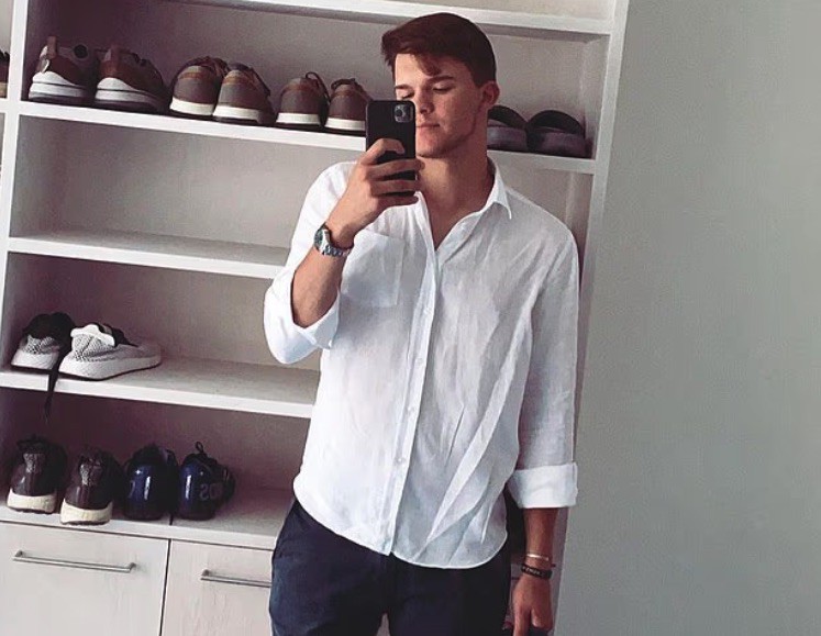 Man taking a mirror selfie in front of a shoe rack.